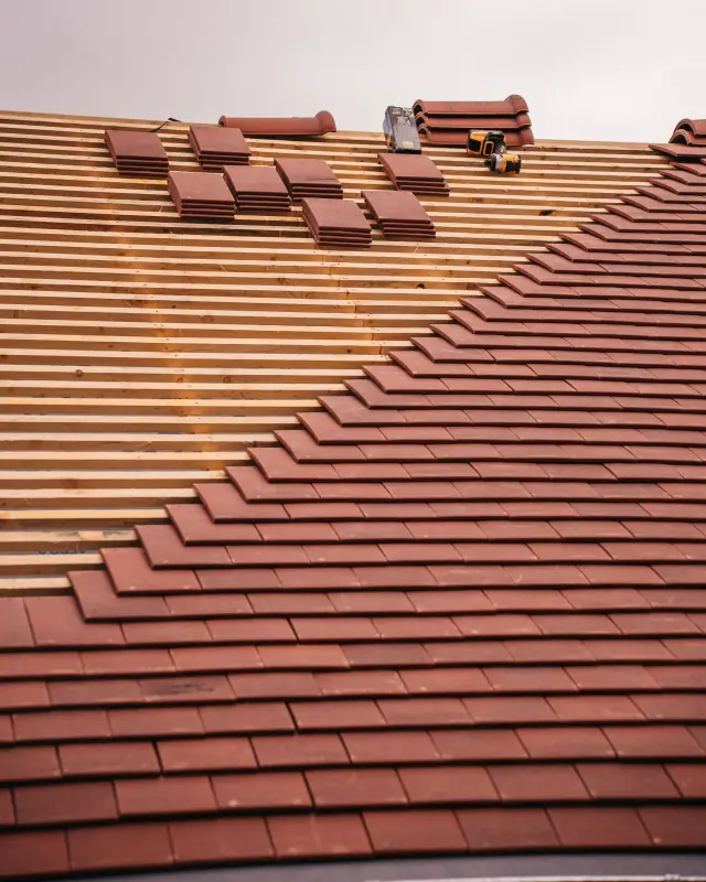 Clay roof tiles half laid on new timber battens