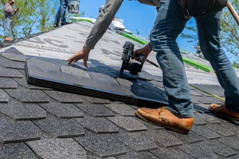 A roofer nailing down a new row of roof shingles